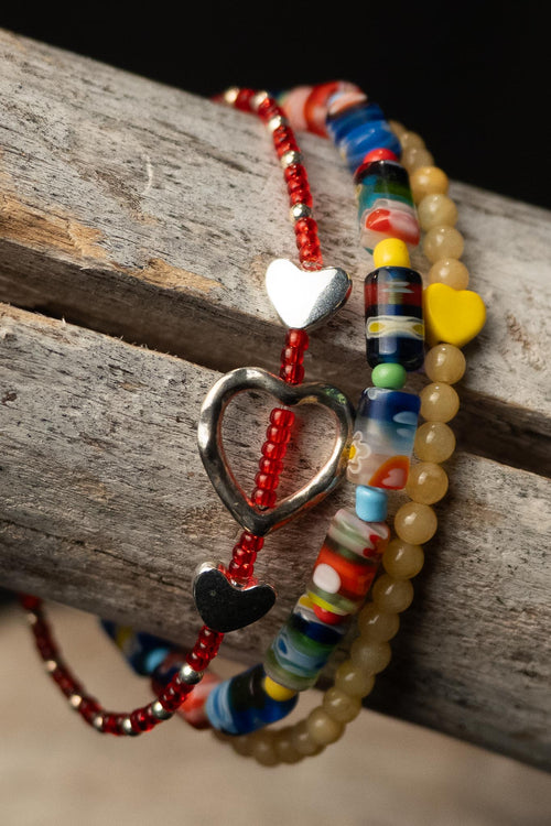 Colorful beaded bracelets with heart-shaped beads on a wooden surface