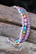 Colorful beaded bracelets with a butterfly charm on a wooden surface