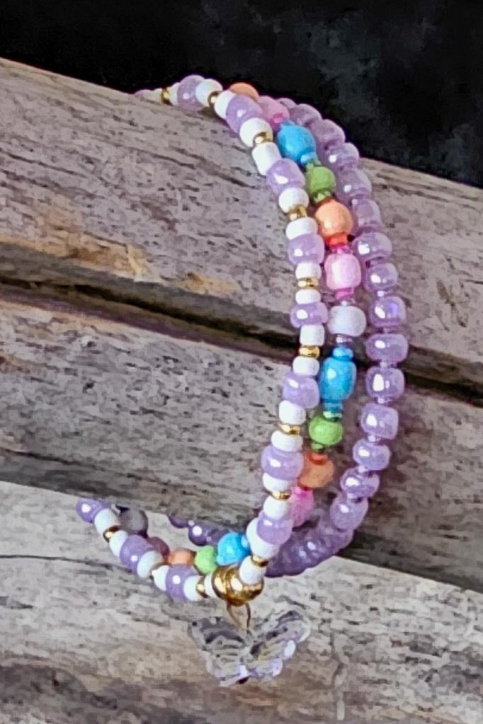 Colorful beaded bracelets with a butterfly charm on a wooden surface