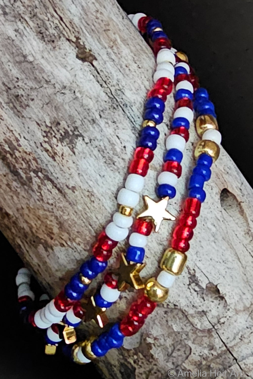 Set of beaded bracelets in red, white, blue, and gold with gold star beads on a wooden surface