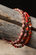 Stack of multicolored beaded bracelets with gold accents on a wooden surface