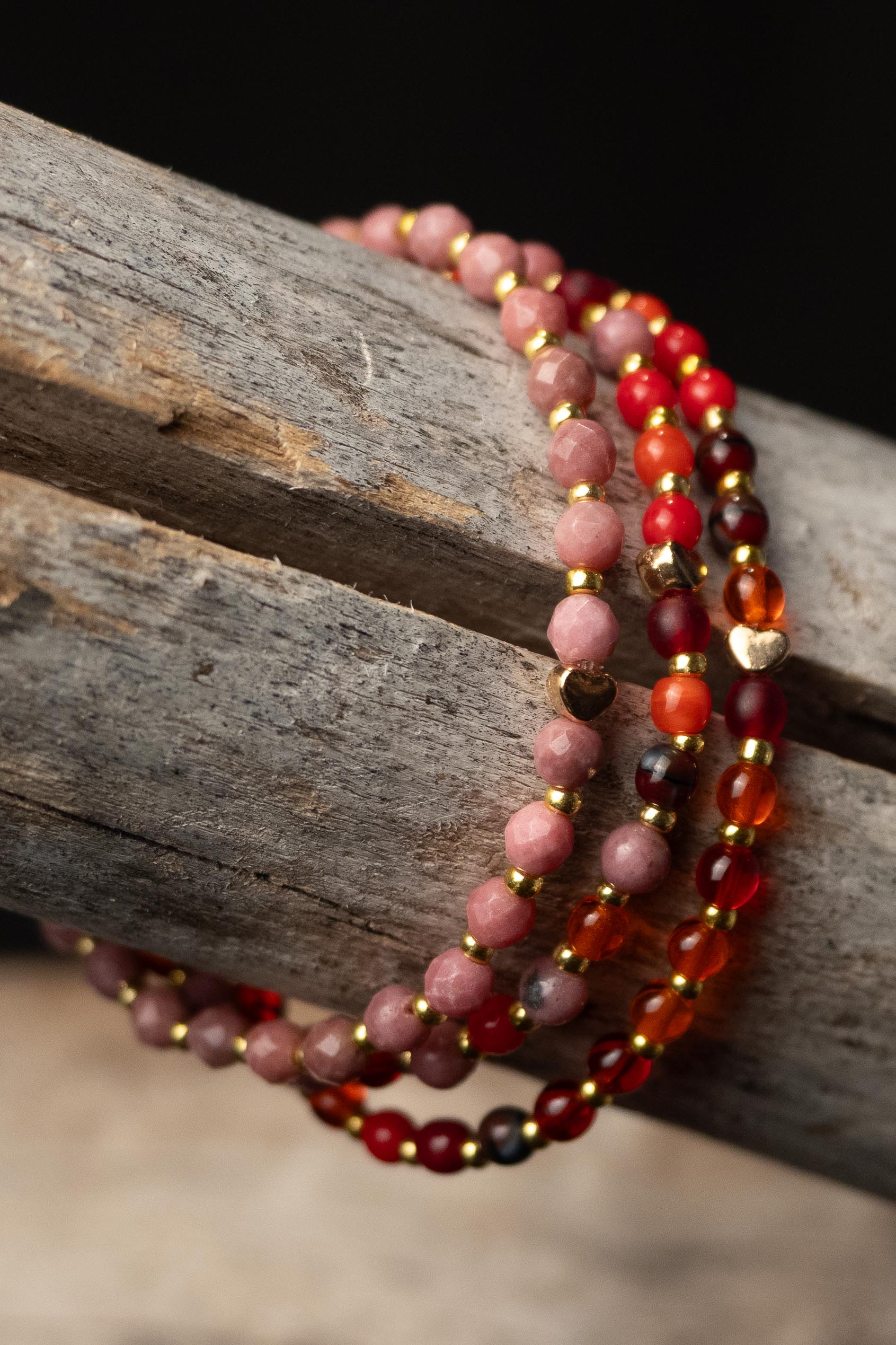 Stack of multicolored beaded bracelets with gold accents on a wooden surface