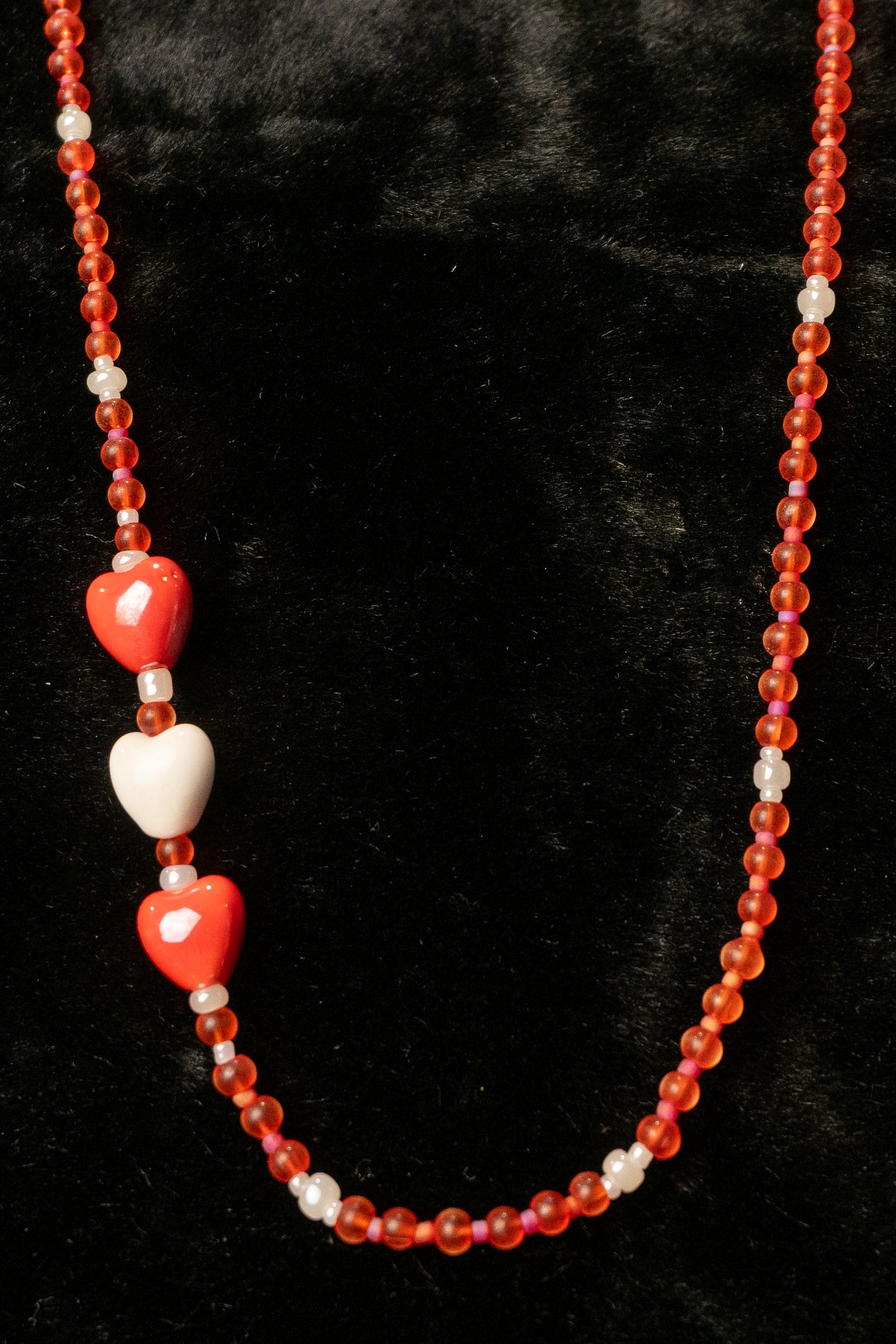 Necklace with red and white beads and heart beads on a black background