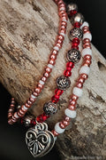 Pink and red beaded bracelets with silver rose beads and heart charms on a wooden surface