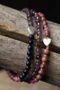 Three beaded bracelets with heart-shaped charms on a wooden surface