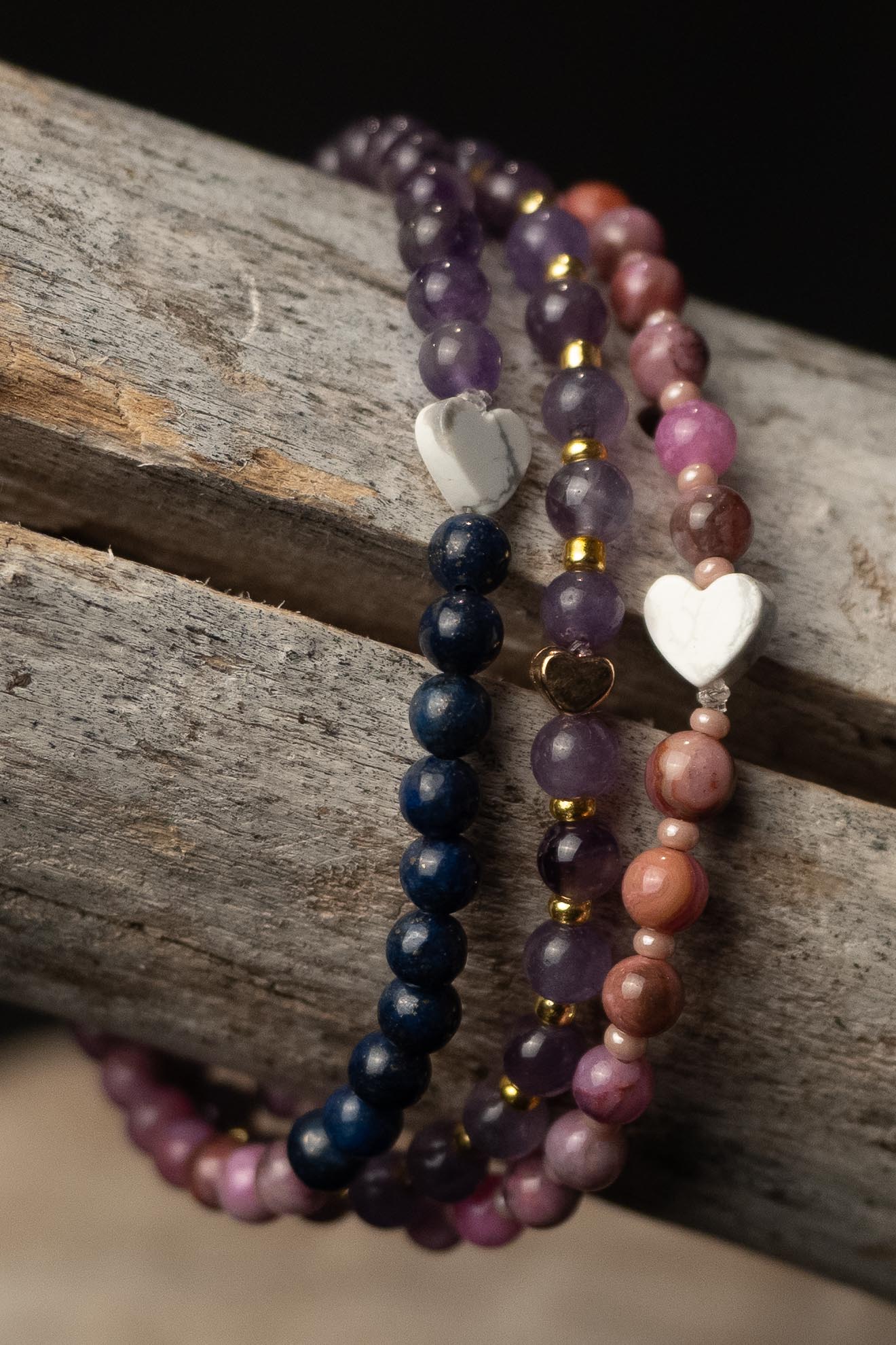Three beaded bracelets with heart-shaped charms on a wooden surface