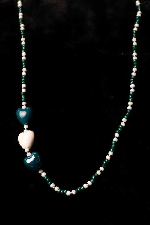 Forest green and white necklace with heart-shaped beads on a black background