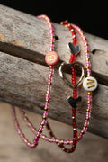 Three beaded bracelets with heart and 'B' 'W' letter charms on a wooden surface
