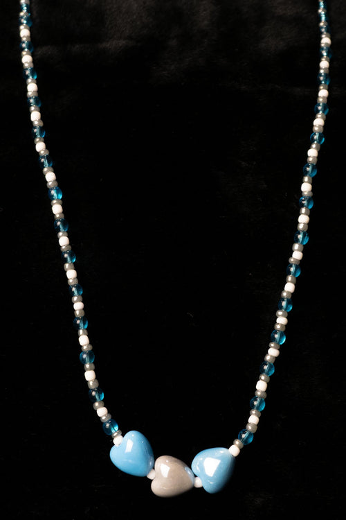 Necklace with blue, gray, and white heart-shaped beads on a black background