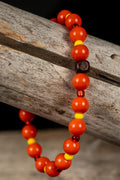 Beaded bracelets with red, yellow, orange and brown beads on a wooden surface