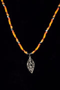 Necklace with beads and a silver leaf pendant on a black background