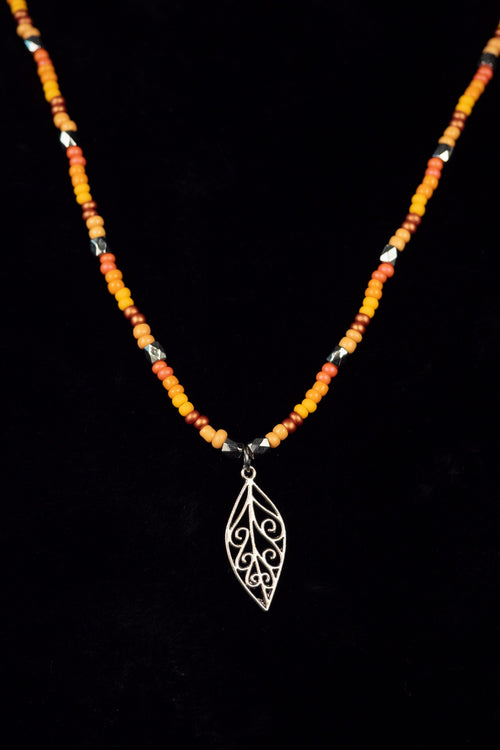 Necklace with beads and a silver leaf pendant on a black background
