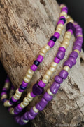 Purple and cream beaded bracelets with a purple heart accent on a wooden surface