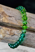 Multi green beaded bracelet on a wooden surface