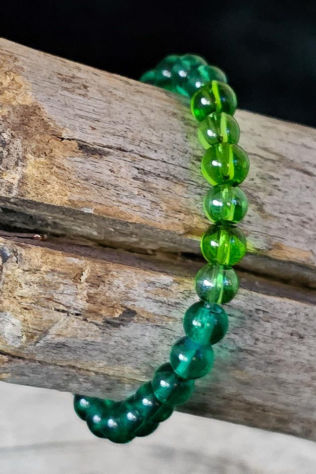 Multi green beaded bracelet on a wooden surface