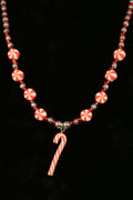 Necklace with candy cane charm and peppermint candy beads on a black background