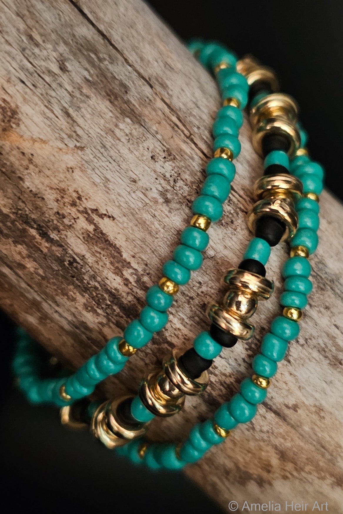 Turquoise beaded bracelets with gold and black accents on a wooden surface