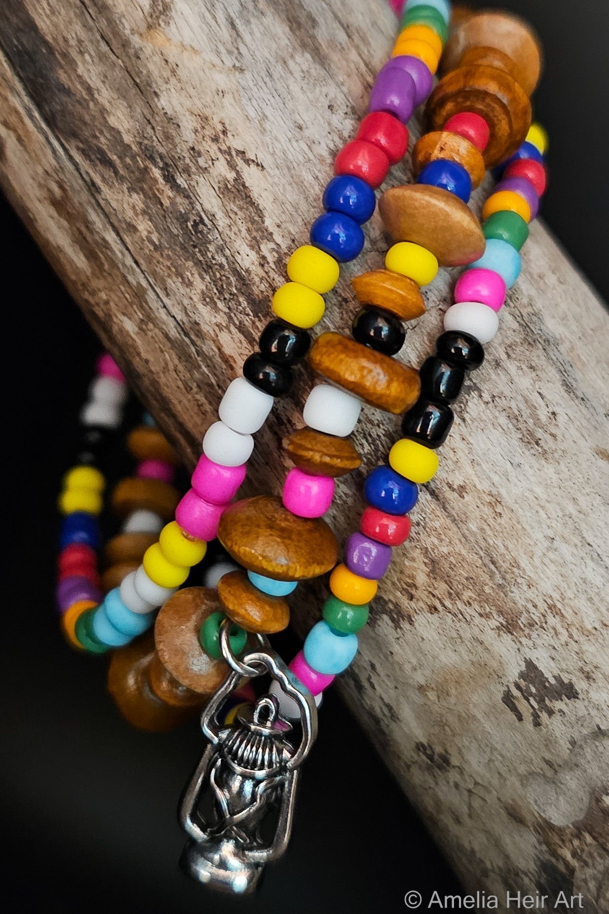 Colorful beaded bracelet with a silver  lantern charm on a wooden surface