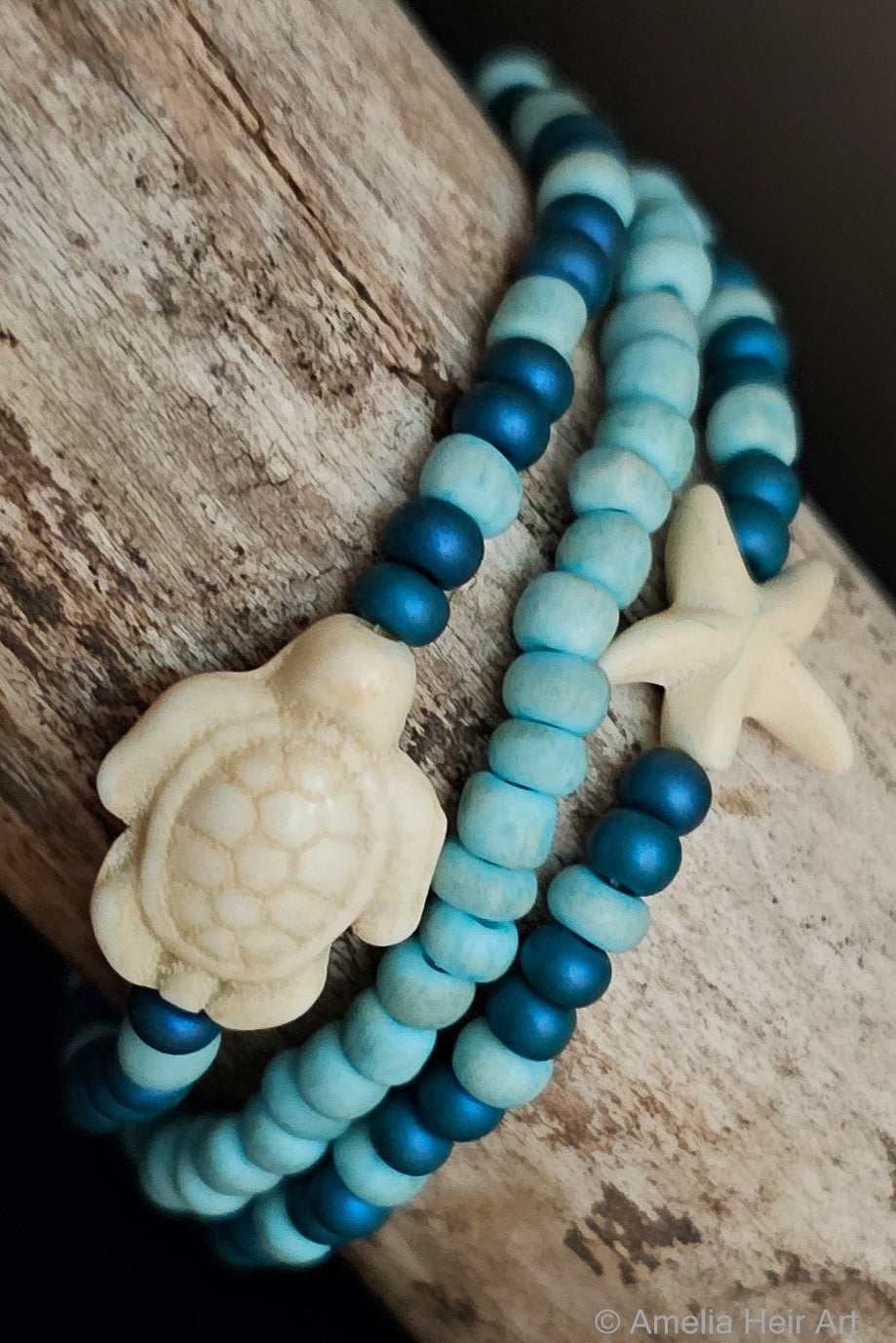 Three blue beaded bracelets with turtle and starfish beads on a wooden surface.