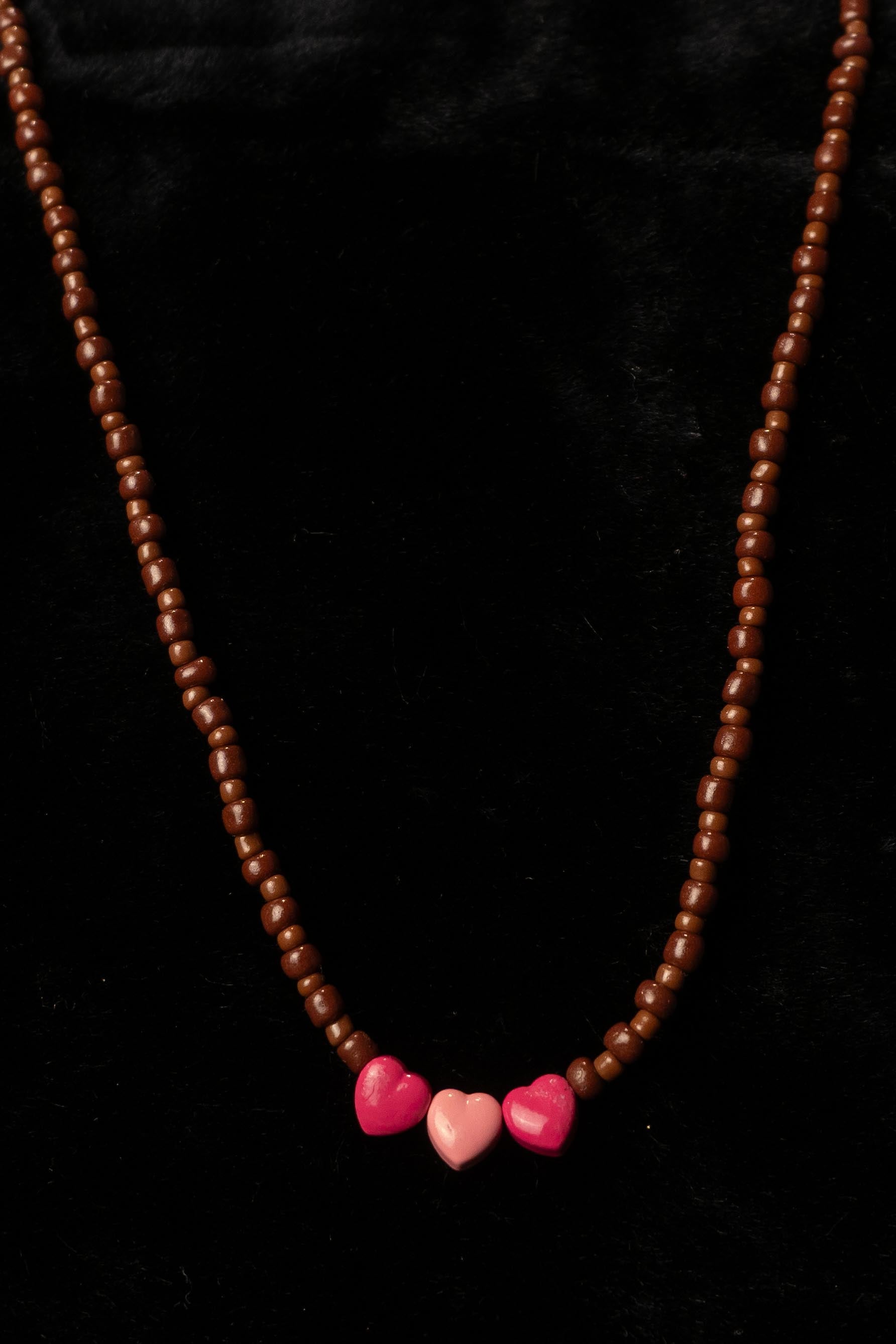 Necklace with brown beads and pink heart-shaped beads on a black background
