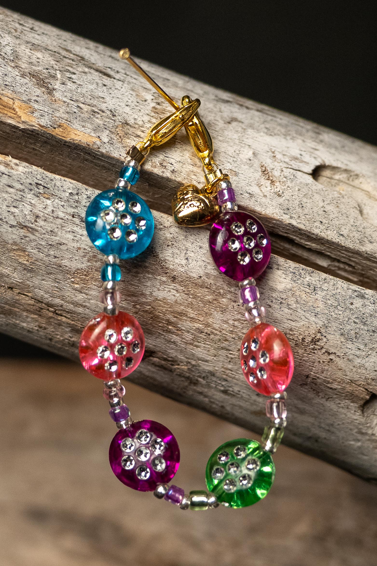 Colorful beaded chain with a tiny heart charm on a wooden surface