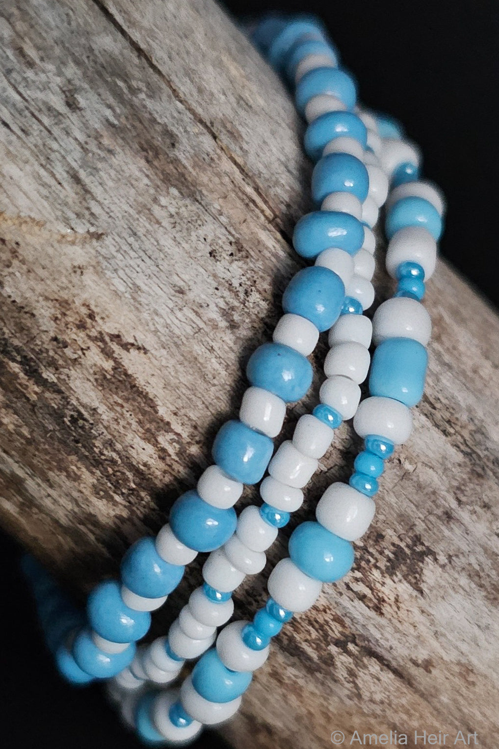 Three blue and white beaded bracelets on a wooden surface