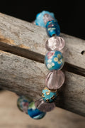 A bracelet with colorful blue and pink floral beads on a wooden surface