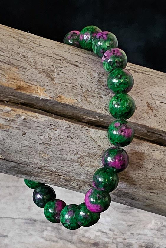 Green and purple beaded bracelet on a wooden surface