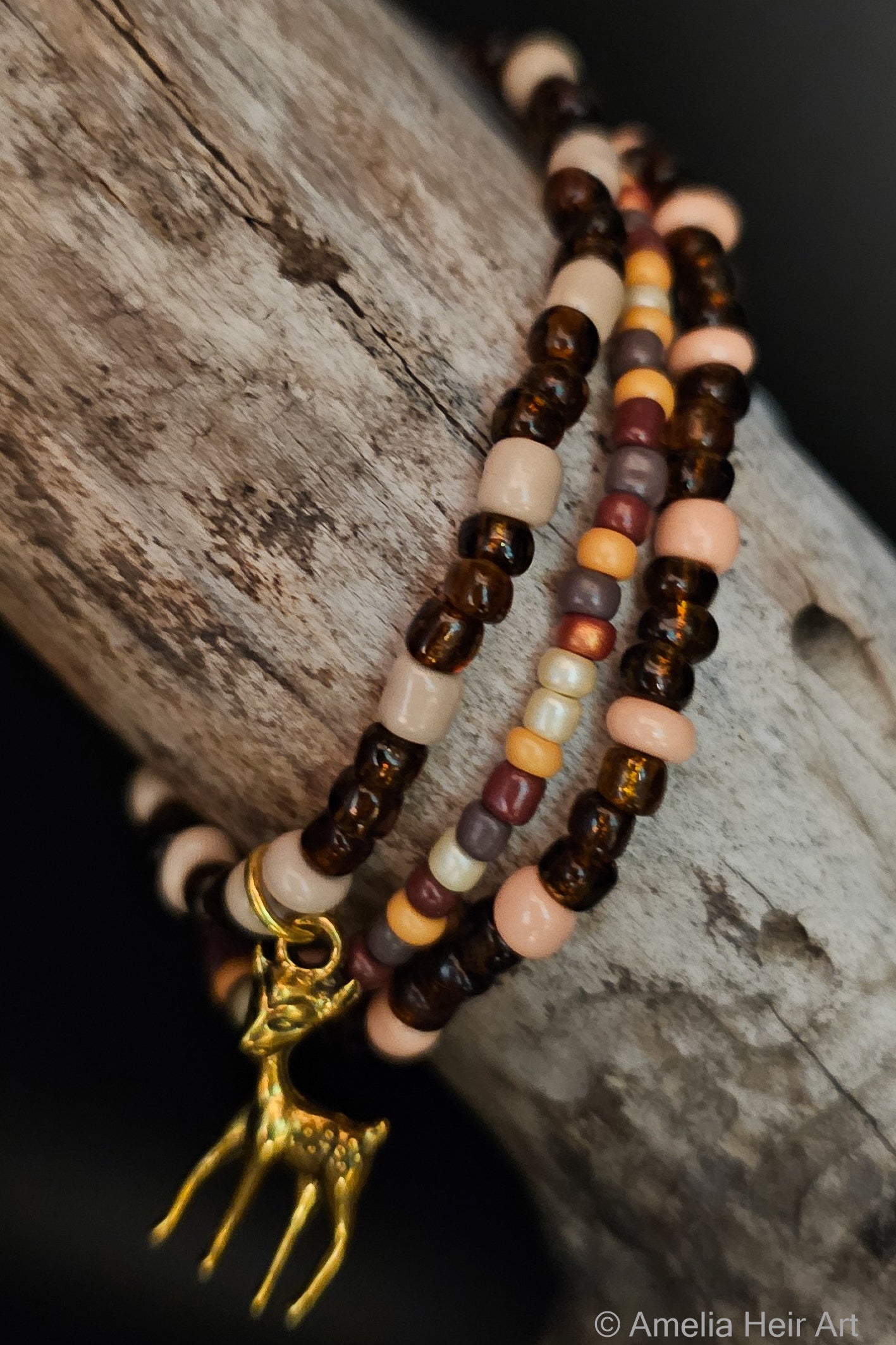 Beaded bracelets with a gold dear charm on a wooden surface