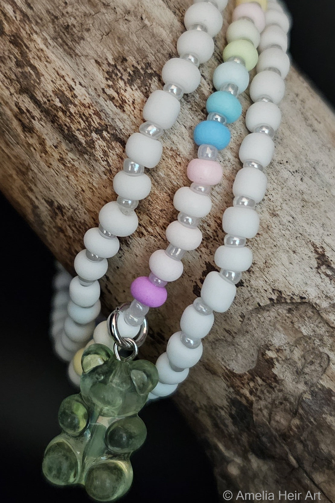 Set of beaded bracelets with colorful beads and gummy-bear shaped charm on a wooden surface