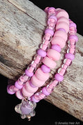Stack of pink and purple beaded bracelets and a star charm on a wooden surface