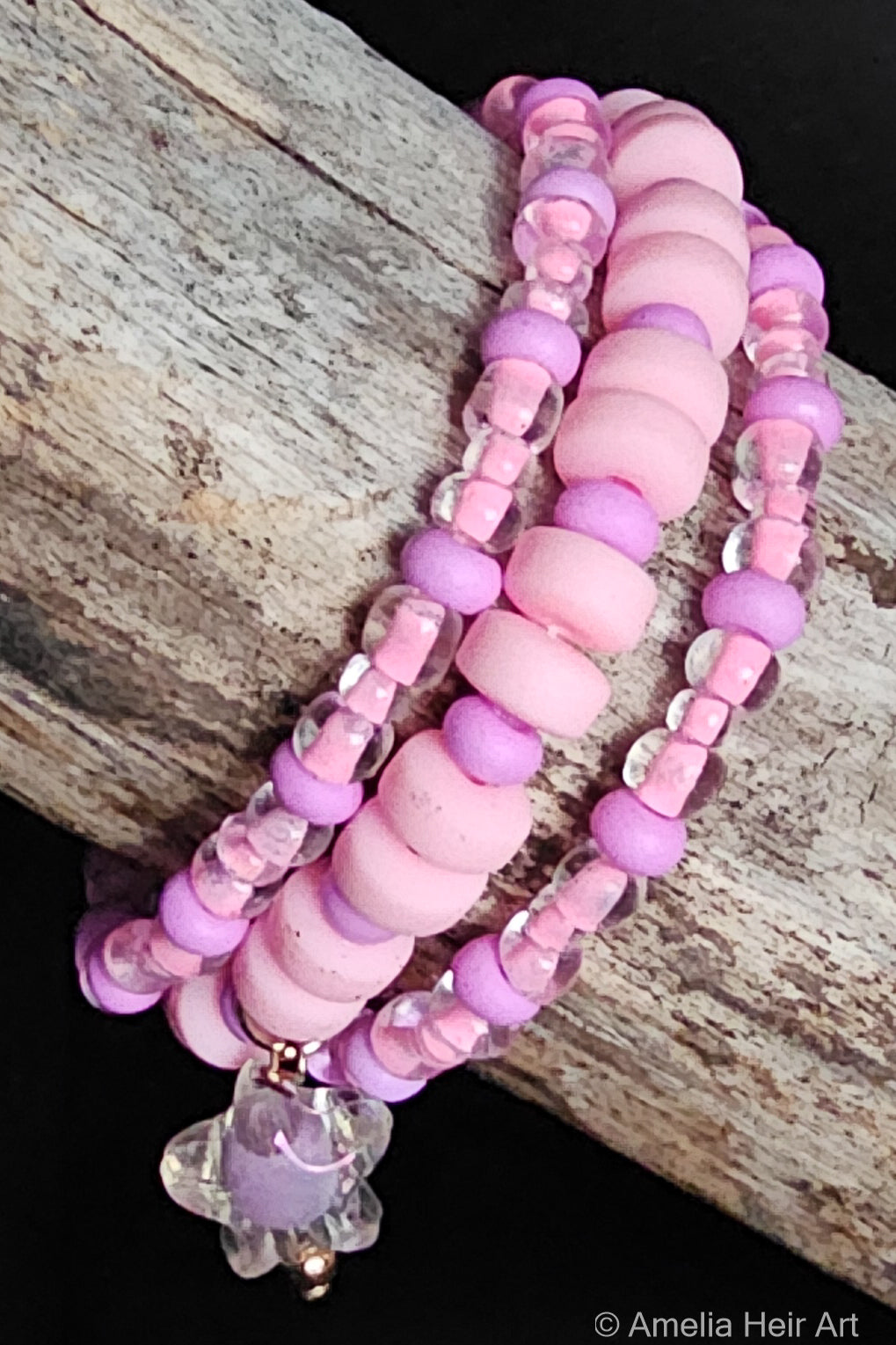 Stack of pink and purple beaded bracelets and a star charm on a wooden surface
