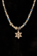 Blue and white necklace with snowflake pendant on a black background