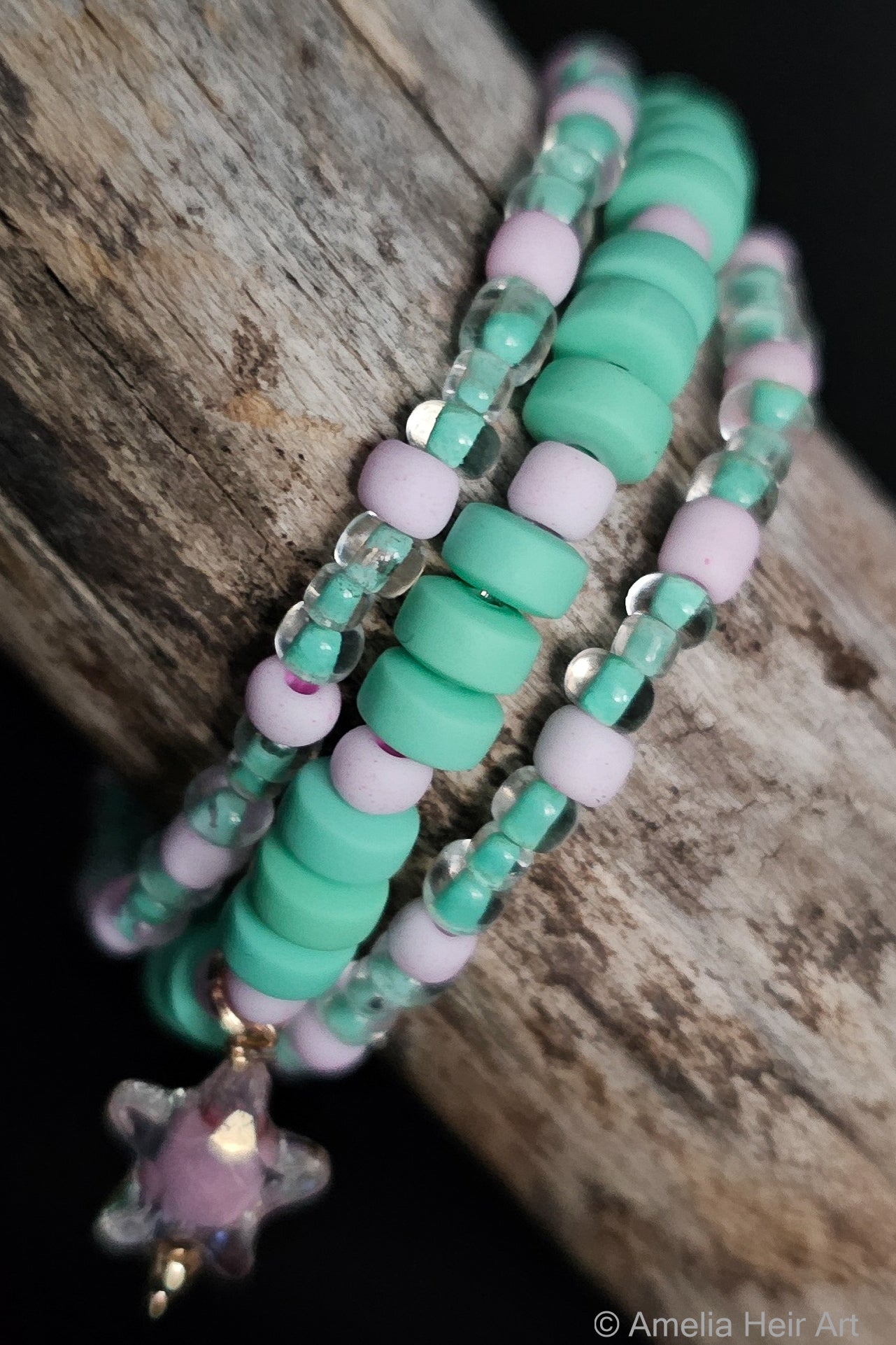 Teel and pink beaded bracelet with a star charm on a wooden surface