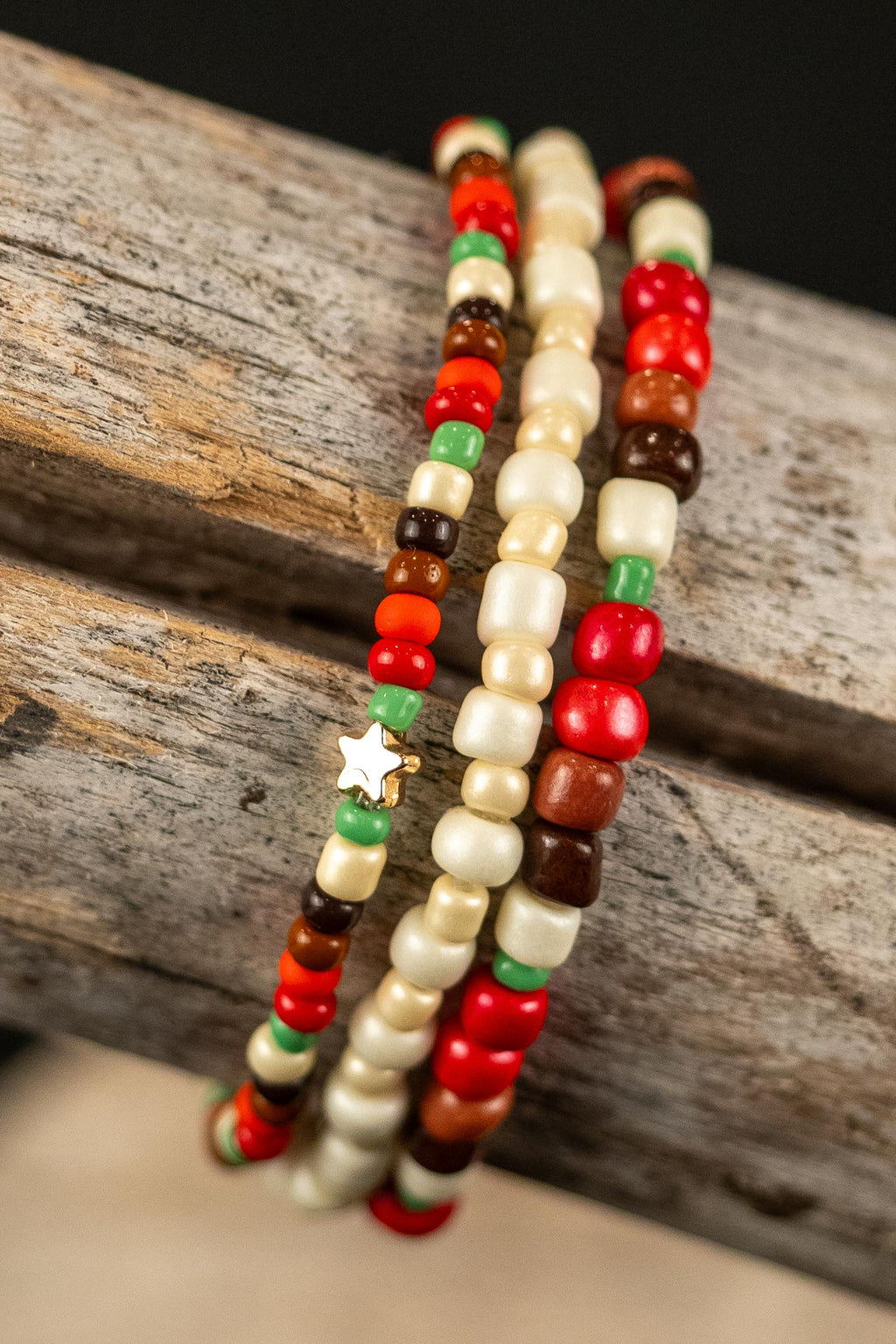 Three beaded bracelets with pink, green, brown, and cream beads on a wooden surface.