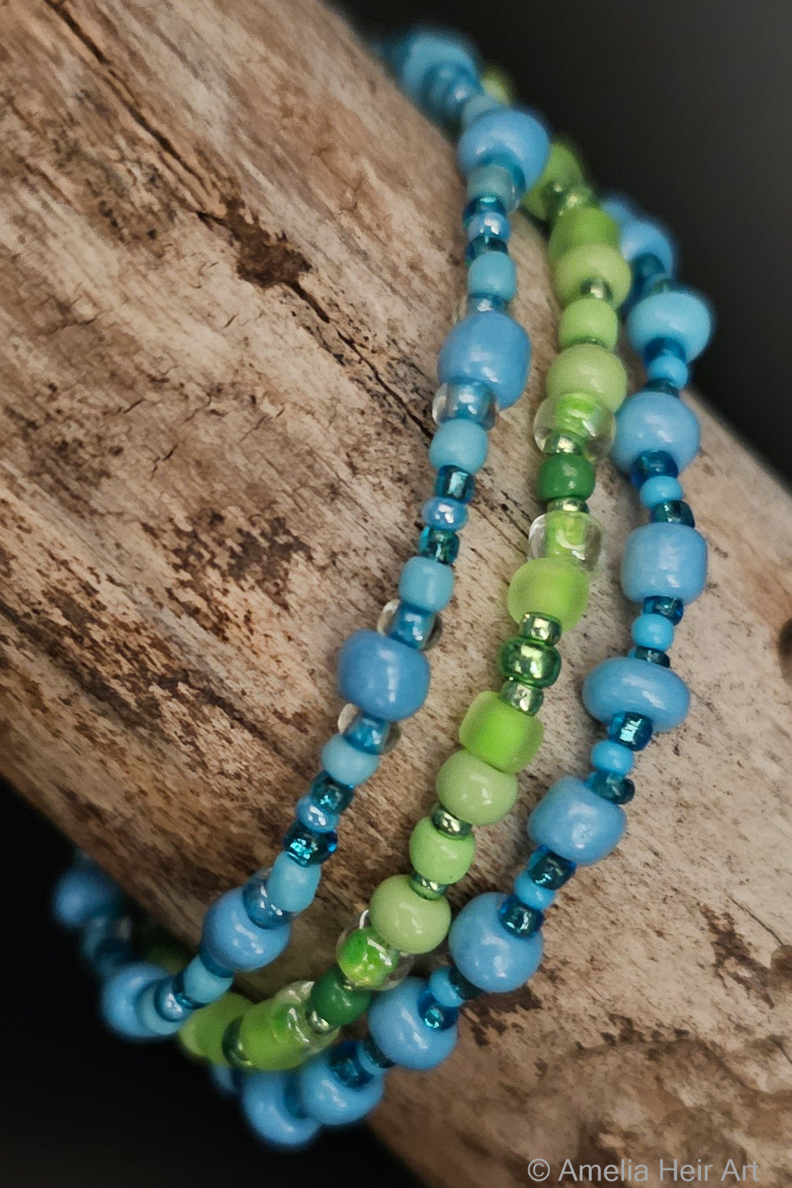 Stack of blue and green beaded bracelets on a wooden surface