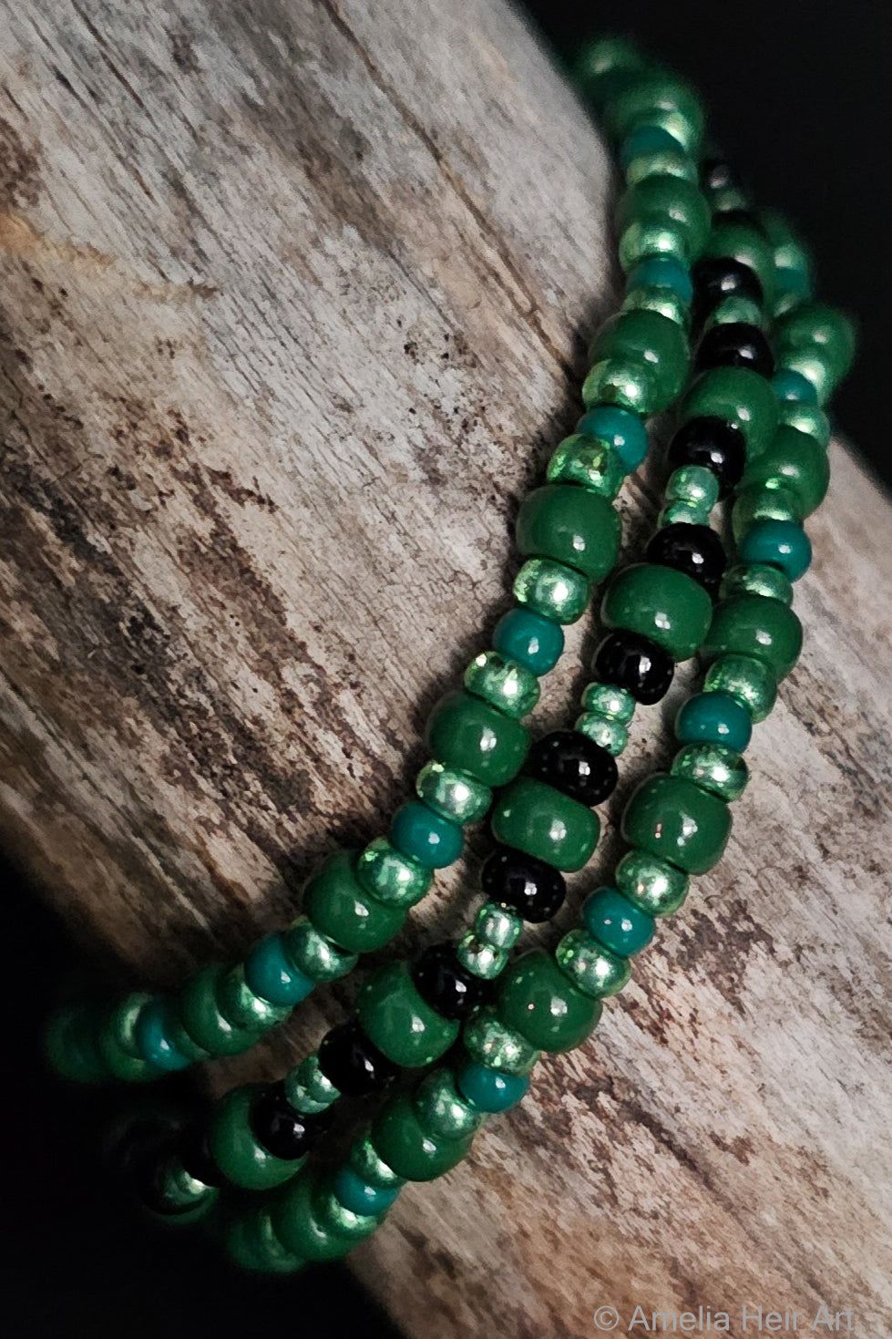 Green and black beaded bracelets on a wooden surface