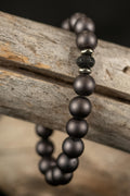 Bracelet with dark gray beads on a wooden surface
