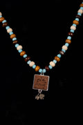 Necklace with blue and wood beads and an 'EXPLORE' pendant with two tiny fools gold pieces on a black background