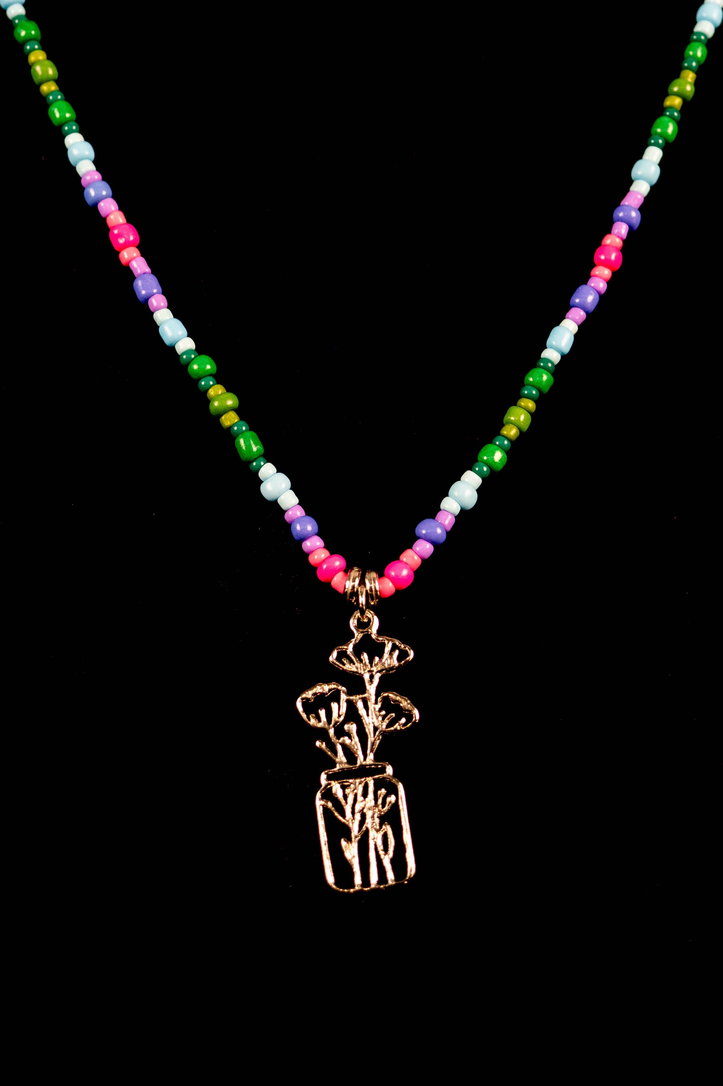 Necklace with colorful beads and a silver wildflower in a mason jar pendant on a black background