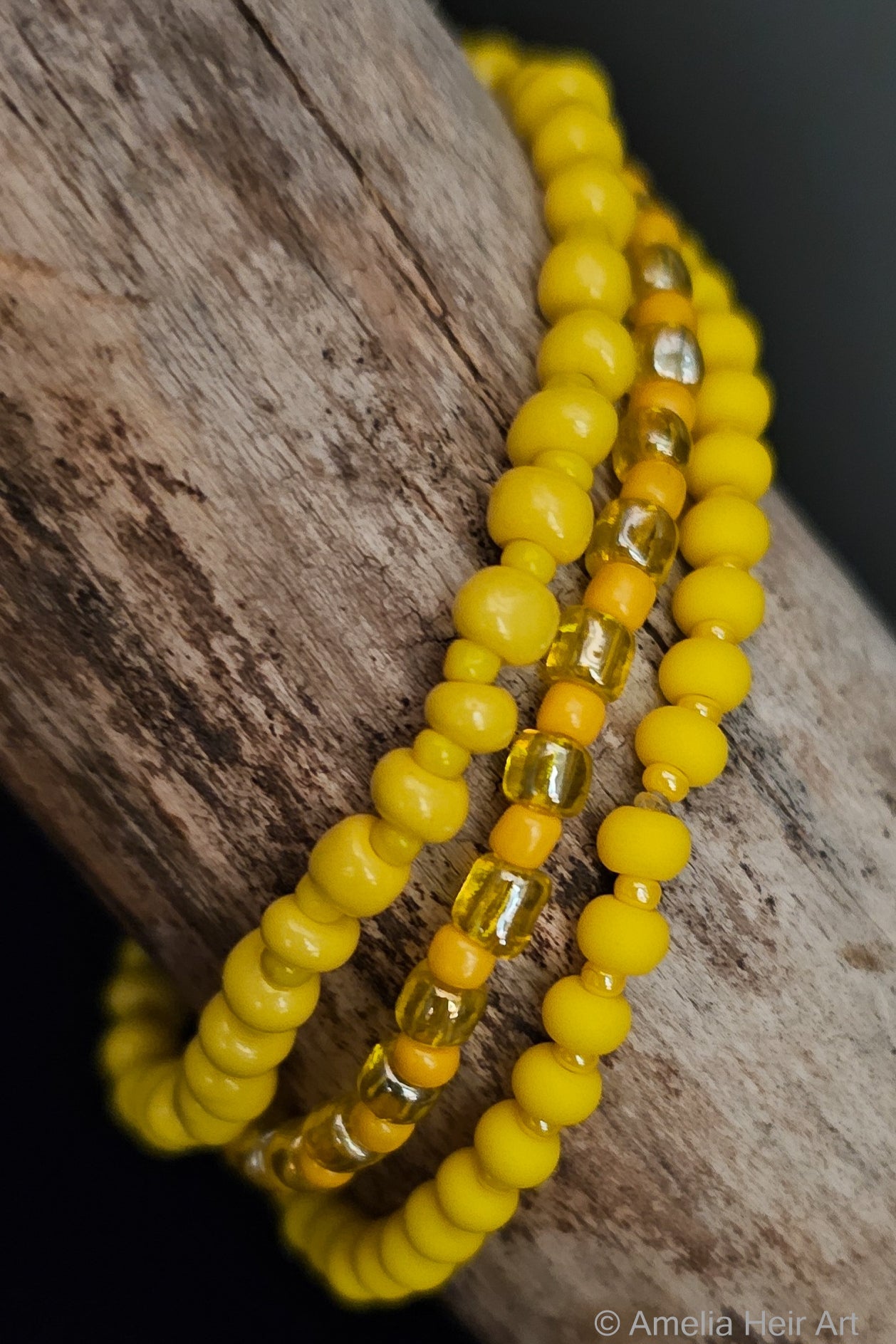 Three yellow beaded bracelets on a wooden surface