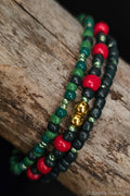 Three beaded bracelets with green, red, and gold beads on a wooden surface.