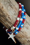 Beaded bracelet with red, white, and blue beads and a white star charm on a wooden surface.