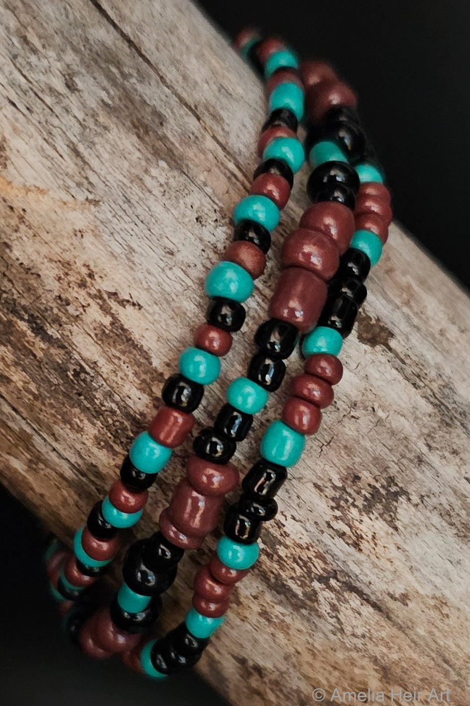 Three beaded bracelets in brown, black, and turquoise on a wooden surface