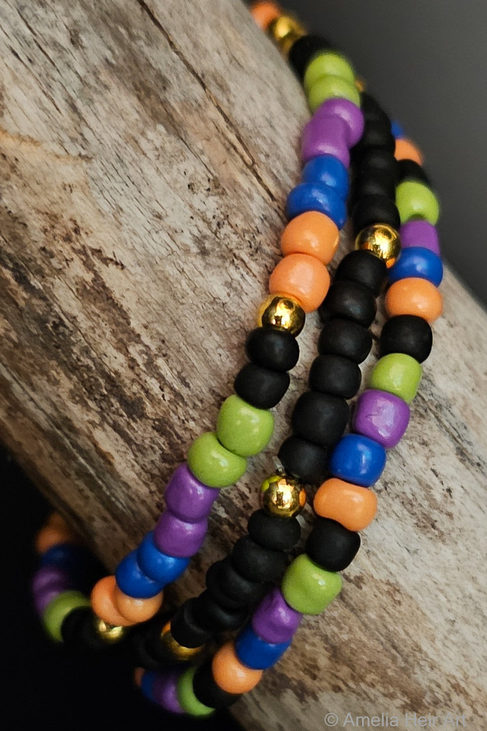 Colorful, black, and gold beaded bracelets on a wooden surface