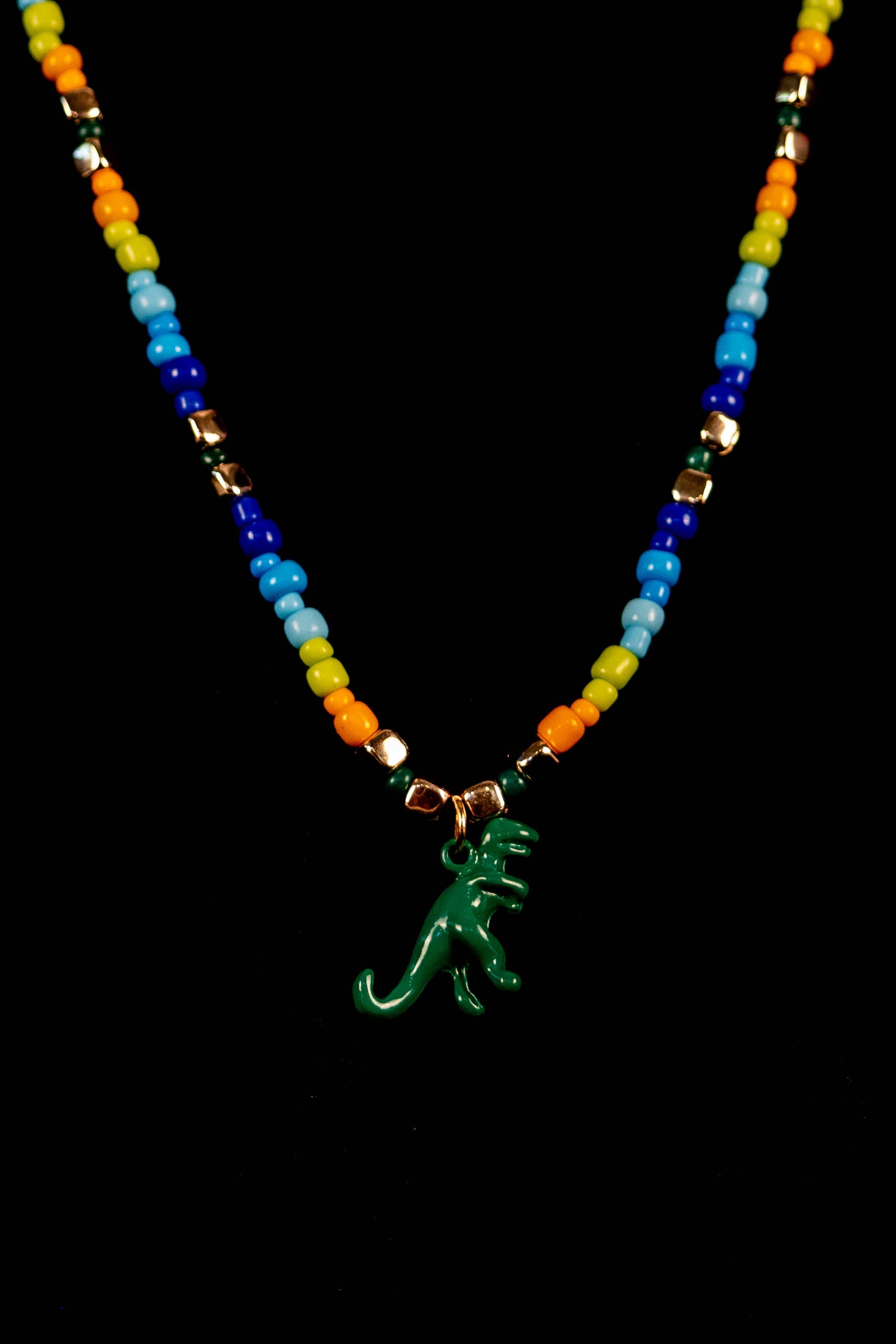 Necklace with colorful beads and a green dinosaur pendant on a black background