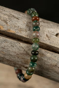 Beaded bracelet with green and brown beads on a wooden surface