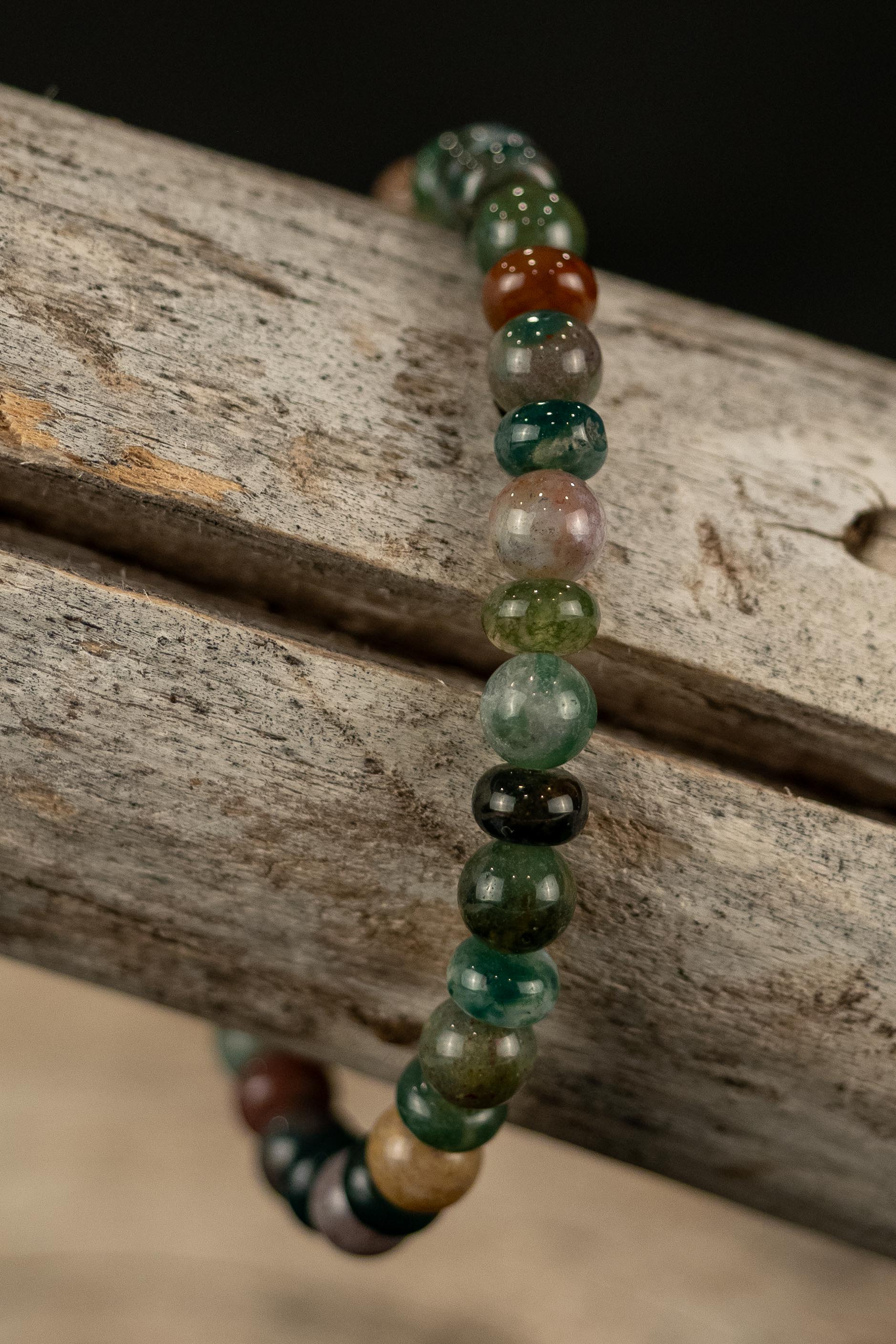 Beaded bracelet with green and brown beads on a wooden surface