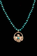 Necklace with turquoise beads and a silver eagle pendant on a black background