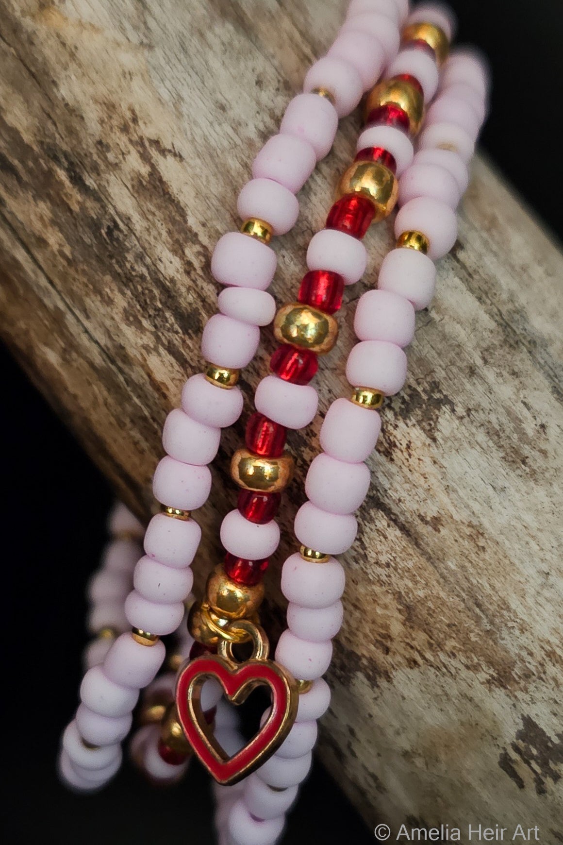 Three beaded bracelets with heart charm on a wooden surface